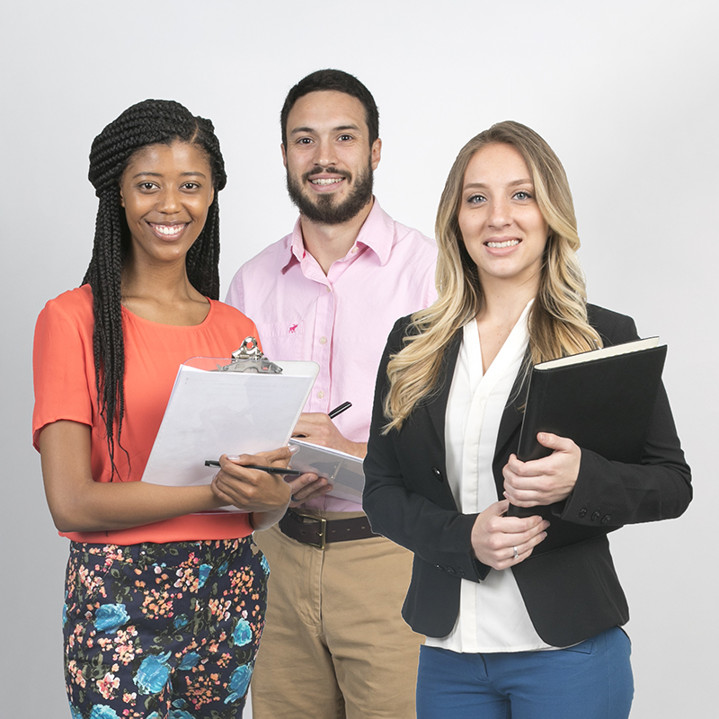 Three graduate students standing with their class materials.