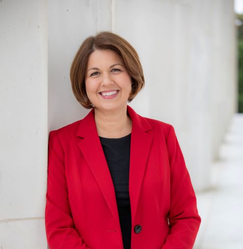 A professional image of Amy wearing a red blazer jacket and a black shirt. 