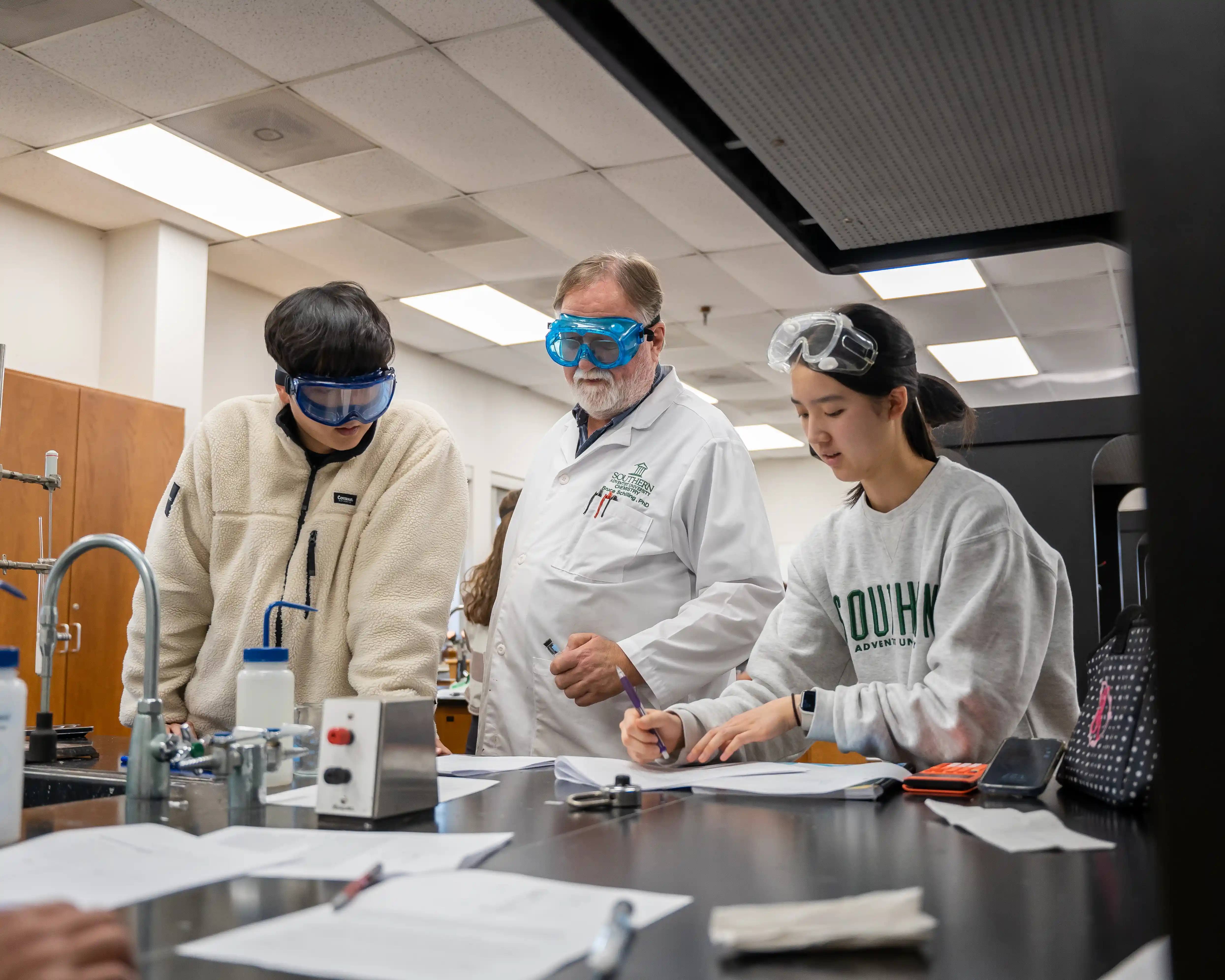 A professor sits next to a student and points out something in a textbook