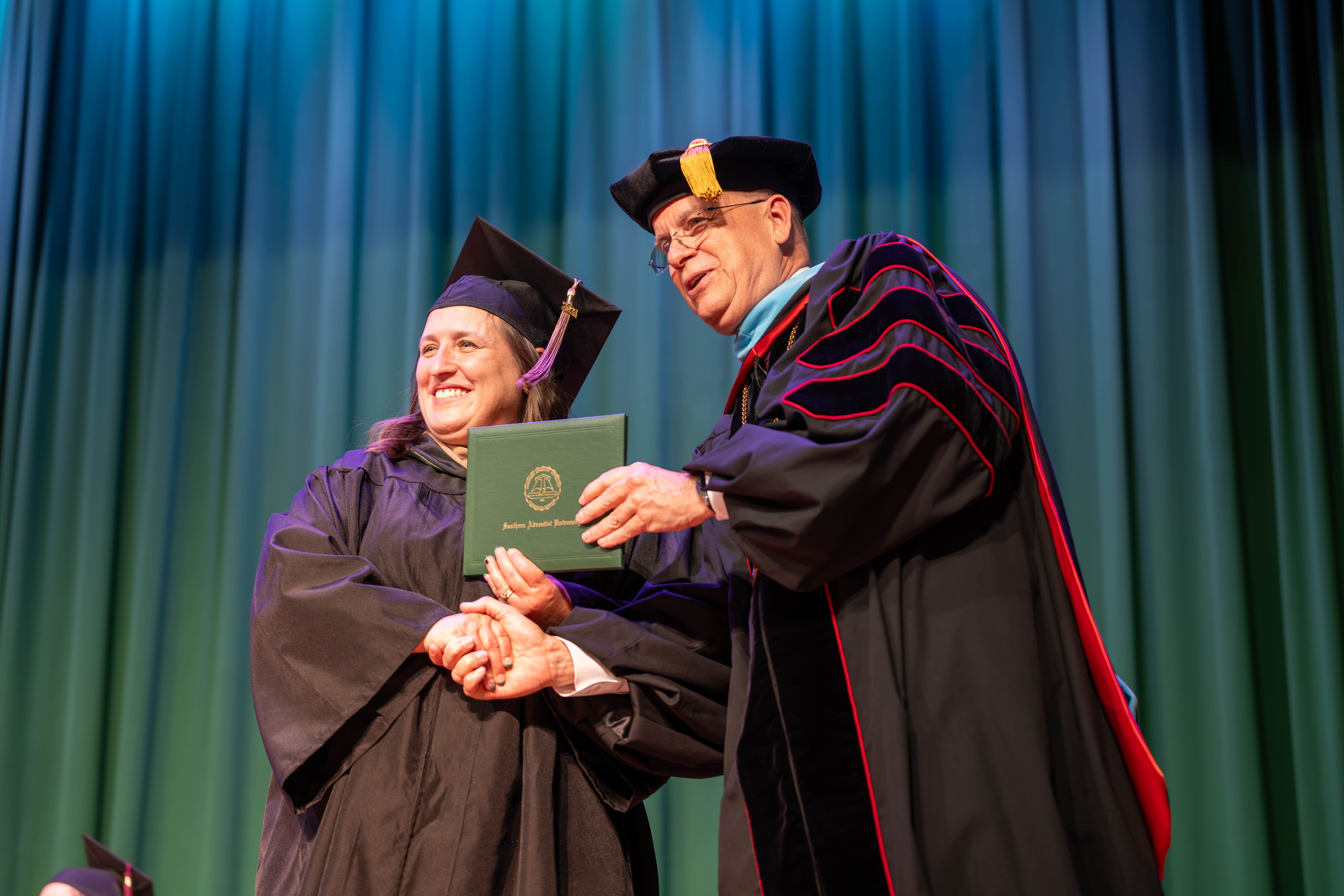 Pamela Burchard receives her diploma from President Ken Shaw as she graduates from the Adult Degree Completion program with a bachelor’s degree in business management.